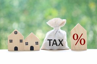 © Monthira - stock.adobe.com Foto: Häuschen und Beute mit Aufschrift Tax