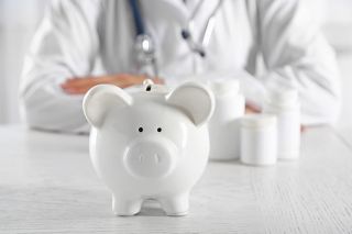 © Africa Studio - stock.adobe.com Foto: Arzt hinter Sparschwein